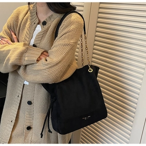 Détail du sac cabas en daim noir avec bandoulière en chaîne dorée et cordon latéral