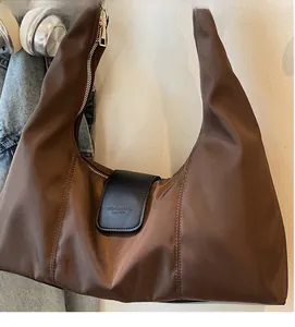 Detail of hobo bag showing brown nylon fabric texture and black leather magnetic flap