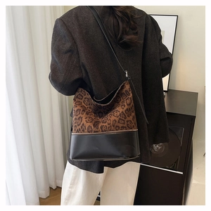 Close-up of leopard print bucket bag with black leather stitching and slim shoulder strap