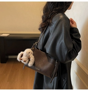 Detail of dark brown vintage shoulder bag with fluffy rabbit charm and fine stitching