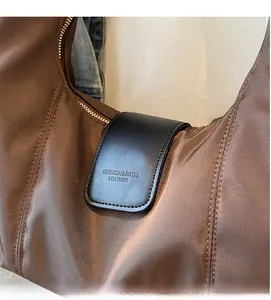 Detail of nylon shoulder bag featuring black leather flap with embossed fashion lettering