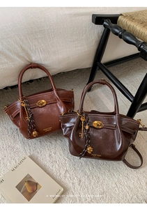 Detail of retro leather bucket bag featuring golden twist lock and vintage textures