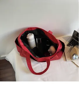 Détail intérieur du sac cabas à carreaux rouges montrant les compartiments de rangement