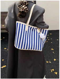 Detailed close-up of blue and white striped canvas tote bag with a white fuzzy keychain