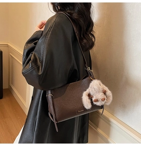 Detail of dark brown lychee leather handbag with cute plush bunny charm on the side