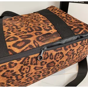 Detailed close-up of smooth black metal zipper pull on large leopard print travel bag