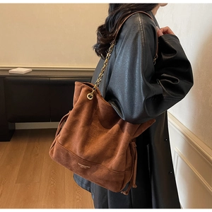 Détail du sac cabas en daim marron avec chaîne dorée et détails de cordon