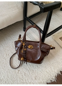 Detail of dark brown leather tote bag with white stitching and gold lock hardware