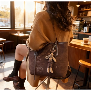 Detail of coffee brown suede tote bag with cat embroidery and a cute rabbit pendant