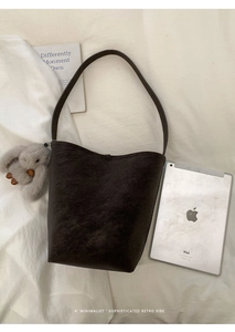 Macro view of dark brown pebbled leather bucket bag with cute plush rabbit charm
