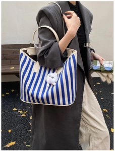 Detail of blue and white striped canvas tote bag with cream leather trim and fluffy charm