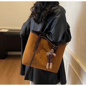 Detail of camel suede tote bag featuring cat embroidery and cute rabbit plush charm