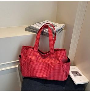 Détail du sac cabas en toile à carreaux rouges avec poche latérale et texture durable