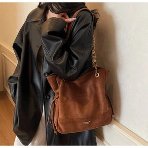 Détail d'un sac cabas en daim marron avec bandoulière en chaîne et détails de cordon à gland