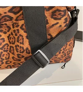 Close-up of leopard print travel bag with adjustable black shoulder strap and metal buckle