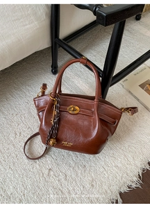 Detailed close-up of dark brown leather bucket bag with vintage gold hardware and logo