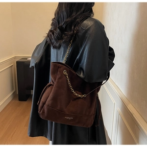 Gros plan d'un sac cabas en daim marron avec détail de chaîne et marquage minimaliste