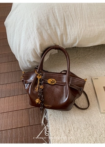 Detail of vintage brown leather bucket bag with gold logo and decorative charms