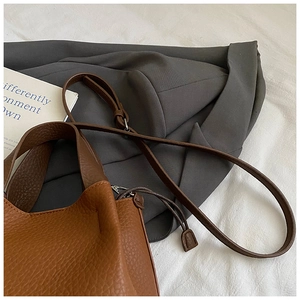 Vue détaillée de la texture du cuir marron à motif litchi de ce sac seau élégant