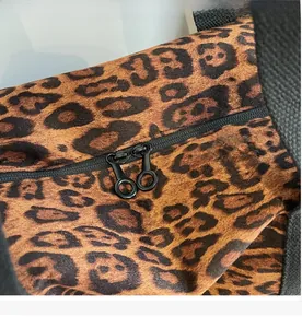 Close-up of leopard print travel bag featuring smooth double black zipper closure