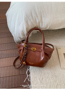 Detail view of brown leather bucket bag with gold clasp and Pan'tor London branding