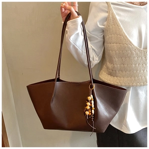 Dark brown matte leather tote bag with stylish wooden bead charm shown on shoulder