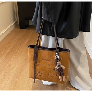 Detail of vintage brown suede tote with cat embroidery and plush rabbit pendant