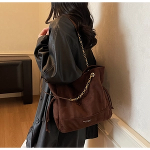 Sac cabas en daim marron foncé avec chaîne dorée et détails de franges sur un mannequin