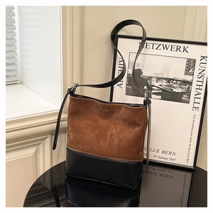 Detail of two-tone bucket bag featuring brown suede and black leather with metal zipper