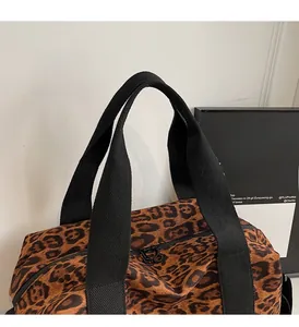Detail of leopard print travel bag featuring sturdy woven handles and double zippers