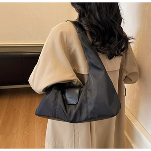 Detail of black nylon hobo bag with wide leather strap and embossed logo texture