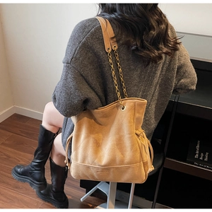 Détail du sac cabas en daim camel montrant les coutures géométriques et la chaîne dorée