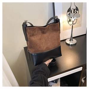 Detailed view of the large bucket bag in brown suede and black leather stitching