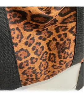 Macro view of leopard print plush fabric texture and black canvas strap detail