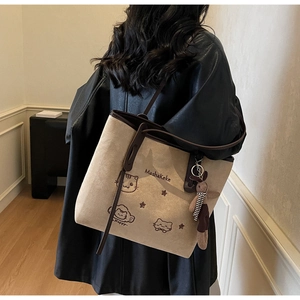 Detail of embroidered tote bag with cat illustration and fluffy rabbit charm