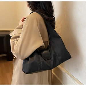 Close-up of black nylon hobo bag with zip closure and embossed leather detail