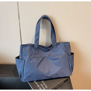 Détail du grand sac cabas à carreaux montrant le motif bleu foncé et les poches latérales
