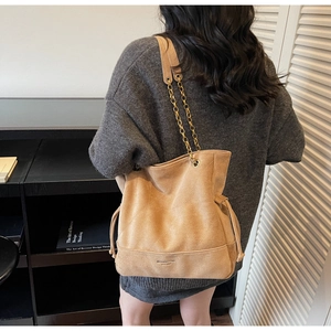 Détail du sac cabas en daim beige avec surpiqûres et bandoulière en chaîne dorée