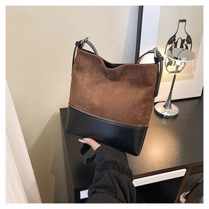 Detail of a brown and black bucket bag showing the suede texture and contrast leather