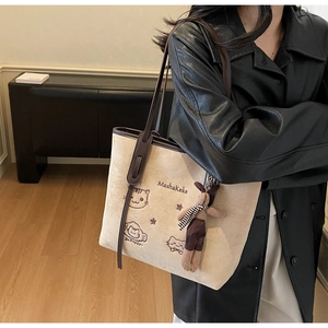 Detailed embroidery of cute cats on a beige suede tote bag with brown leather straps