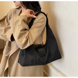 Detailed view of a black nylon hobo bag styled with a stylish khaki trench coat