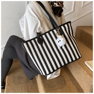 Chic striped canvas tote bag detail featuring black and white patterns and a plush charm