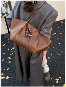 Detail of dark brown tote bag with vintage wooden beads and tassel in autumn setting