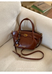 Detail of a brown leather bucket bag with gold hardware and hanging key charms