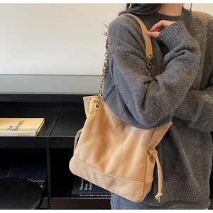 Détail du sac cabas en daim camel avec motif matelassé et bandoulière chaîne dorée