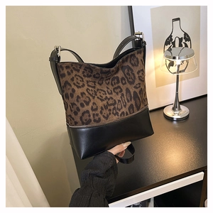 Detail of leopard print and black leather bucket bag featuring a decorative zipper