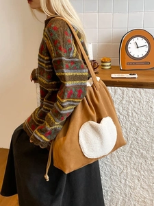 Brown plush tote bag with white heart patch worn by model in casual autumn style