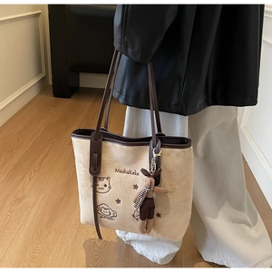 Detail of beige tote bag with cat embroidery, leather trim and bunny charm