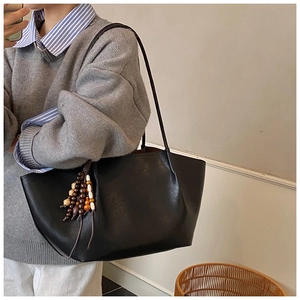 Close-up of black matte tote bag with vintage wooden bead tassel for daily commute