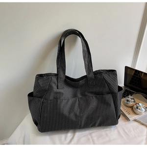 Détail du sac cabas à carreaux avec poche latérale posé près d'un ordinateur portable